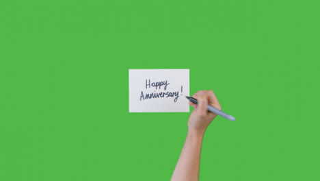 Woman-Writing-Happy-Anniversary-on-Paper-with-Green-Screen