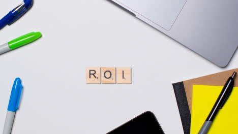 Stop-Motion-Business-Concept-Above-Desk-Wooden-Letter-Tiles-Forming-Acronym-ROI-1