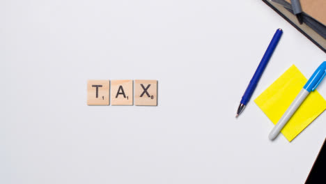 Stop-Motion-Business-Concept-Above-Desk-Wooden-Letter-Tiles-Forming-Word-Tax