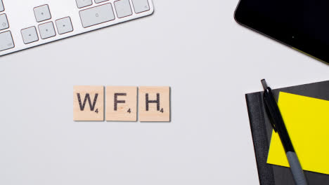 Stop-Motion-Business-Concept-Above-Desk-Wooden-Letter-Tiles-Forming-Acronym-WFH-1