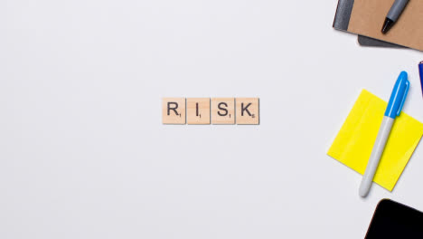 Stop-Motion-Business-Concept-Above-Desk-Wooden-Letter-Tiles-Forming-Word-Risk