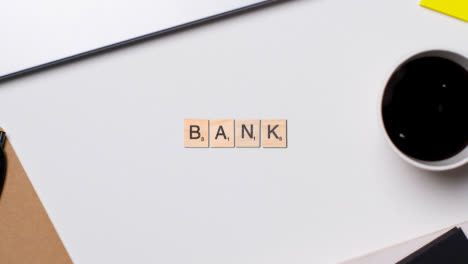 Stop-Motion-Business-Concept-Above-Desk-Wooden-Letter-Tiles-Forming-Word-Bank