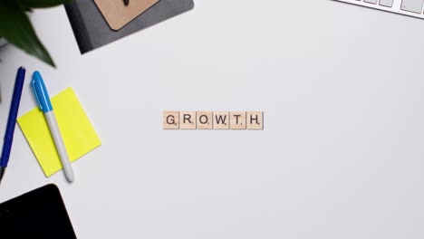 Stop-Motion-Business-Concept-Above-Desk-Wooden-Letter-Tiles-Forming-Word-Growth