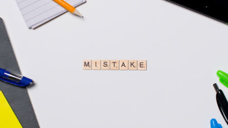 Stop-Motion-Business-Concept-Above-Desk-Wooden-Letter-Tiles-Forming-Word-Mistake