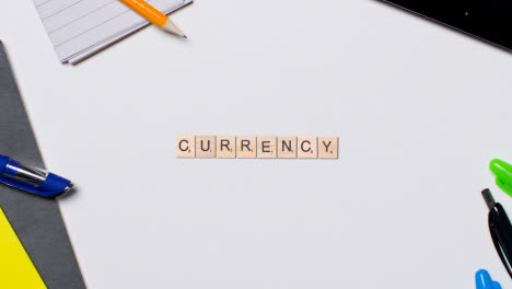 Stop-Motion-Business-Concept-Above-Desk-Wooden-Letter-Tiles-Forming-Word-Currency