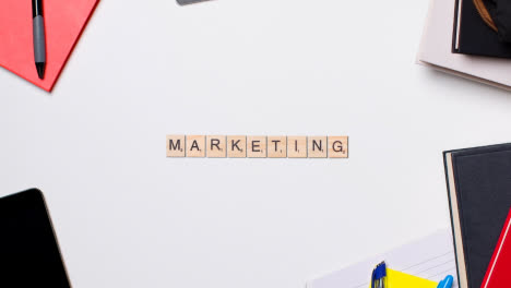 Stop-Motion-Business-Concept-Above-Desk-Wooden-Letter-Tiles-Forming-Word-Marketing