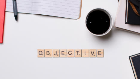 Stop-Motion-Business-Concept-Above-Desk-Wooden-Letter-Tiles-Forming-Word-Objective-1
