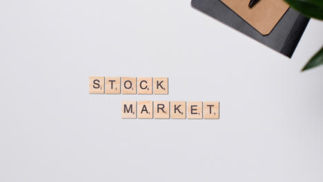 Stop-Motion-Business-Concept-Above-Desk-Wooden-Letter-Tiles-Forming-Words-Stock-Market