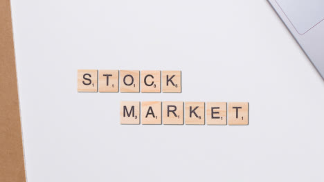 Stop-Motion-Business-Concept-Above-Desk-Wooden-Letter-Tiles-Forming-Words-Stock-Market-1