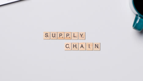 Stop-Motion-Business-Concept-Above-Desk-Wooden-Letter-Tiles-Forming-Words-Supply-Chain
