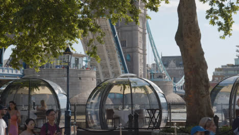 Crowd-Of-Summer-Tourists-Walking-By-Tower-Bridge-London-England-UK-With-Restaurant-Pods-In-Foreground