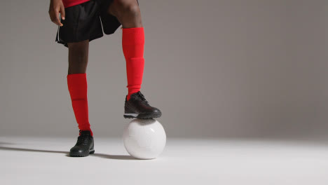 Close-Up-Of-Male-Footballer-In-Studio-Resting-Foot-On-Ball