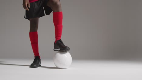 Close-Up-Of-Male-Footballer-In-Studio-Resting-Foot-On-Ball