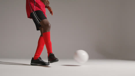 Close-Up-Of-Male-Footballer-In-Studio-Kicking-And-Passing-Ball
