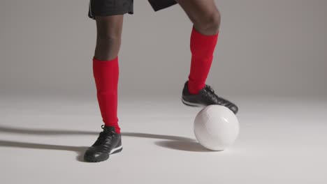 Studio-Close-Up-Of-Male-Footballer-Wearing-Club-Kit-Dribbling-With-Ball-
