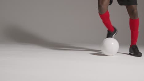 Studio-Close-Up-Of-Male-Footballer-Wearing-Club-Kit-Dribbling-With-Ball-1