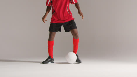 Studio-Close-Up-Of-Male-Footballer-Wearing-Club-Kit-Dribbling-With-Ball-3