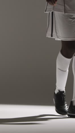Vertical-Video-Close-Up-Of-Male-Footballer-Wearing-Club-Kit-Kicking-Or-Passing-Ball