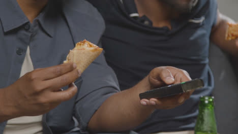 Amigos-Multiculturales-Sentados-En-El-Sofá-En-Casa-Viendo-La-Televisión-Comiendo-Pizza-Para-Llevar-A-Domicilio-1