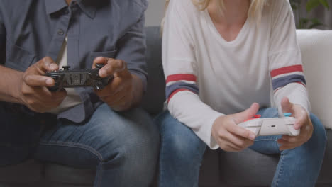 Close-Up-Of-Multi-Cultural-Friends-Or-Couple-Sitting-On-Sofa-At-Home-Gaming-Online-