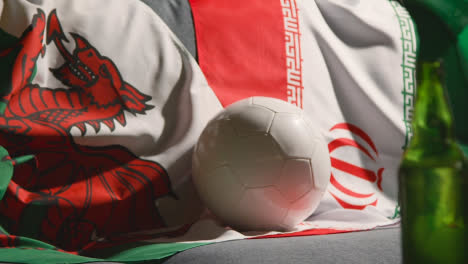 Sofa-In-Der-Lounge-Mit-Walisischer-Und-Iranischer-Flagge-Und-Ball,-Während-Sich-Die-Fans-Darauf-Vorbereiten,-Fußballspiele-Im-Fernsehen-Zu-Sehen-2