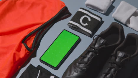 Foto-Plana-De-Estudio-De-Botas-De-Fútbol-Entrenamiento-Bib-Capitanes-Brazalete-Y-Teléfono-Móvil