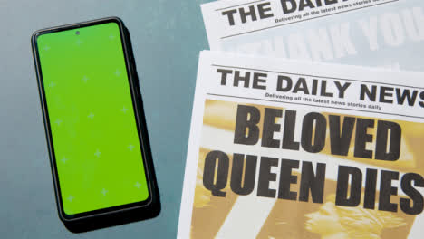 Tracking-Shot-of-Queen-Elizabeth-Death-Newspaper-Headlines-with-Green-Screen-Phone-01