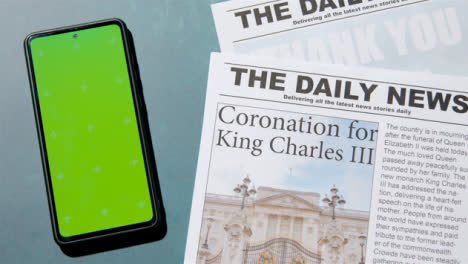 Tracking-Shot-of-King-Charles-III-Coronation-Newspaper-Headlines-with-Green-Screen-Phone