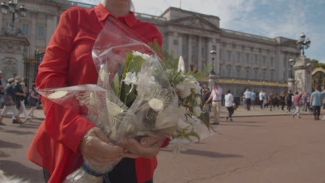 Close-Up-Shot-of-Mourner-Holding-Flowers-Outside-Buckingham-Palace