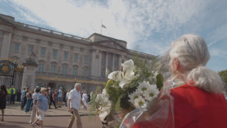 Close-Up-Shot-of-a-Mourner-Holding-Flowers-Outside-Buckingham-Palace