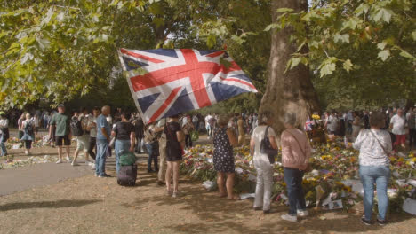 Wide-Shot-of-Floral-Tributes-and-Mourners-In-Green-Park