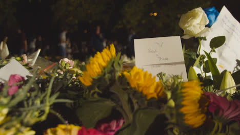Close-Up-Shot-of-Floral-Tributes-and-Mourners-In-Green-Park-London