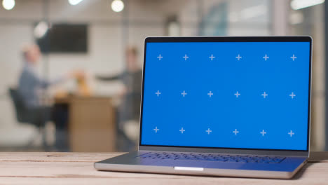 Laptop-Mit-Blauem-Bildschirm-Auf-Dem-Schreibtisch-In-Einem-Geschäftigen-Modernen-Büro-1