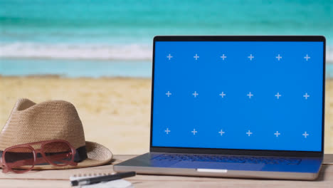 Laptop-Mit-Blauem-Bildschirm-Auf-Dem-Tisch-Mit-Urlaubsstrand-Und-Wellen-Im-Hintergrund