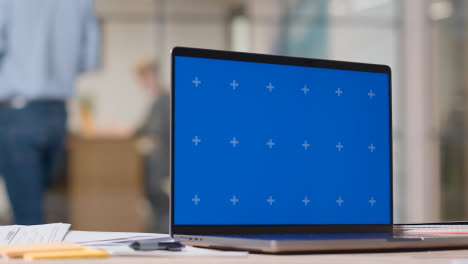 Blue-Screen-Laptop-On-Desk-In-Busy-Modern-Office-3