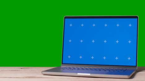 Blue-Screen-Laptop-On-Table-With-Green-Screen-Background