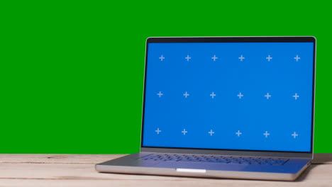 Blue-Screen-Laptop-On-Table-With-Green-Screen-Background-1