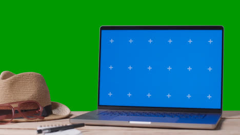 Blue-Screen-Laptop-Auf-Dem-Tisch-Mit-Urlaubszubehör-Und-Green-Screen-Hintergrund-1