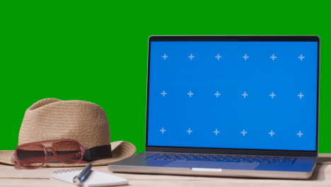Blue-Screen-Laptop-On-Table-With-Holiday-Accessories-And-Green-Screen-Background-2