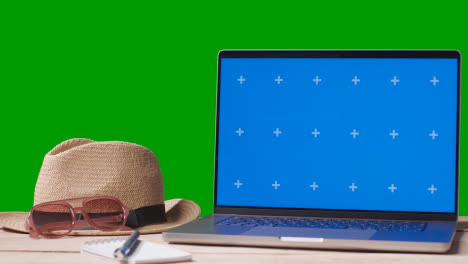Blue-Screen-Laptop-On-Table-With-Holiday-Accessories-And-Green-Screen-Background-3