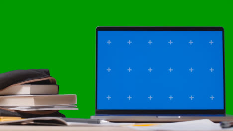 Blue-Screen-Laptop-With-Books-On-Table-With-Green-Screen-Background-Education-Concept