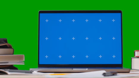 Blue-Screen-Laptop-With-Books-On-Table-With-Green-Screen-Background-Education-Concept-1