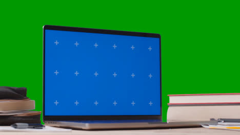 Blue-Screen-Laptop-With-Books-On-Table-With-Green-Screen-Background-Education-Concept-5