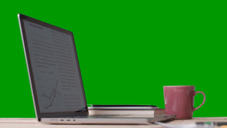 Laptop-Auf-Dem-Schreibtisch,-Der-Die-Finanzielle-Leistung-Gegen-Den-Grünen-Bildschirm-Zeigt