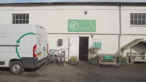 Exterior-Of-UK-Food-Bank-Building-With-Vans-Making-Deliveries