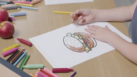 Close-Up-Of-Child-At-Home-Colouring-In-Picture-Of-Burger-At-Table-1