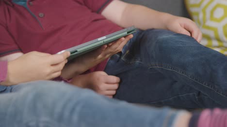 Close-Up-Of-Two-Children-Sitting-On-Sofa-At-Home-Digital-Tablet-Together