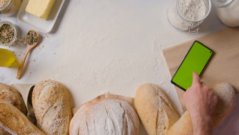 Überkopfaufnahme-Von-Frisch-Gebackenen-Brotlaiben-Auf-Marmorarbeitsfläche-Mit-Greenscreen-Handy