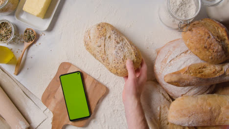 Überkopfaufnahme-Von-Frisch-Gebackenen-Brotlaiben-Auf-Marmorarbeitsfläche-Mit-Greenscreen-Handy-1