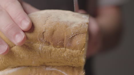 Close-Up-Of-Person-Cutting-Slices-Of-Fresh-Bread-From-Loaf-On-Wooden-Table-2
